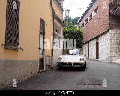 Castellarquato, Italie - 22 juin 2024 Rallye drapeau d'argent , voiture décapotable italienne blanche classique garée dans une rue étroite typiquement italienne, dans le sh Banque D'Images