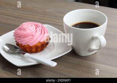 Gâteau à la crème et tasse de café. Le gâteau repose sur une soucoupe. Près d'une cuillère à café. Banque D'Images