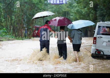 Pékin, province chinoise d'Anhui. 23 juin 2024. Les gens marchent sur une route goudronnée dans le comté de Shexian, ville de Huangshan, province d'Anhui, dans l'est de la Chine, 23 juin 2024. Des tempêtes de pluie ont frappé la ville de Huangshan dimanche. Crédit : du Yu/Xinhua/Alamy Live News Banque D'Images