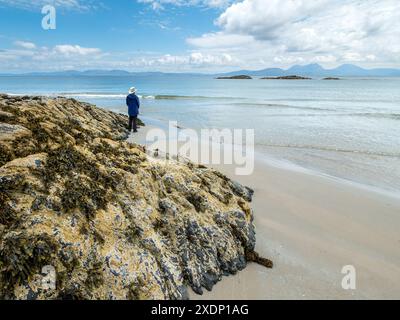 Les Paps de montagne du Jura sont visibles à l'horizon depuis la plage de Port a Chapuill sur l'île voisine de Colonsay dans les Hébrides intérieures, en Écosse, au Royaume-Uni Banque D'Images