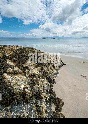 Les Paps de montagne du Jura sont visibles à l'horizon depuis la plage de Port a Chapuill sur l'île voisine de Colonsay dans les Hébrides intérieures, en Écosse, au Royaume-Uni Banque D'Images