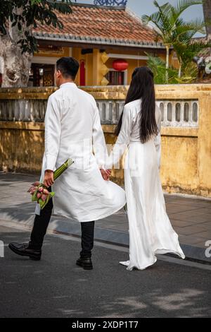 Photo d'un couple asiatique vêtu de vêtements blancs dans la vieille ville de Hoi an Vietnam. Jeune marié et mariée portant des vêtements blancs traditionnels. Belle ASI Banque D'Images