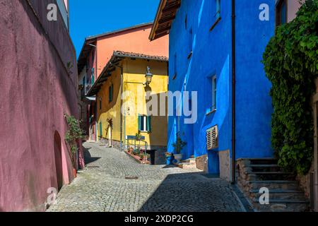 Rue pavée étroite et maisons rouges, jaunes, oranges et bleues dans la petite ville de Monforte d'Alba, Piémont, Italie. Banque D'Images