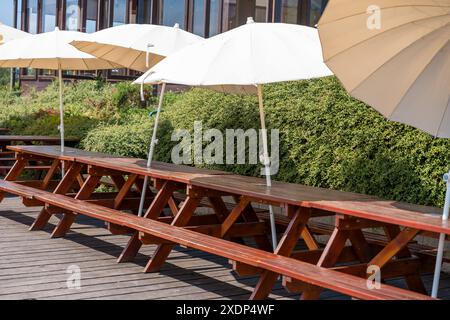 Tables de pique-nique avec parasols dans une terrasse extérieure ensoleillée Banque D'Images