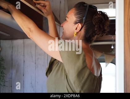 femme ouvrant l'armoire supérieure du fourgon de camping-car Banque D'Images