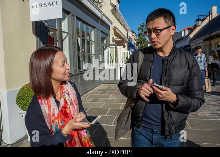 Serris, France, couples, touristes chinois, Shopping, la Vallée Village, Centre commercial Discount, banlieues de Paris, Talking on Street Banque D'Images