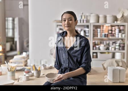 Artiste de céramique asiatique assis dans un studio tenant de l'argile Banque D'Images