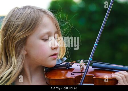 Gros plan d'une fille avec une expression pacifique jouant du violon Banque D'Images