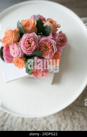 Gros plan d'un bouquet de roses roses roses et pêches sur une table blanche. Banque D'Images