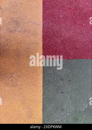 Gros plan de Crosswalk peint orange moutarde, rouge canneberge et gris Banque D'Images