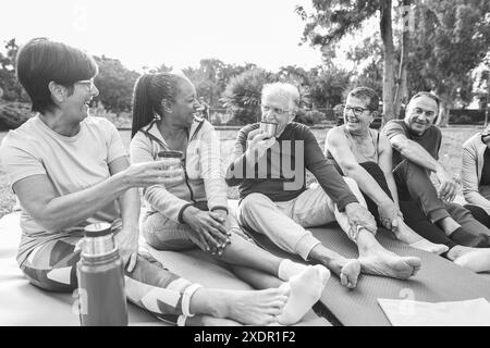 Amis seniors discutant et buvant du thé vert chaud après le cours de yoga en plein air - mode de vie sain pour les personnes matures et concept sportif - Focus sur l'afrique Banque D'Images