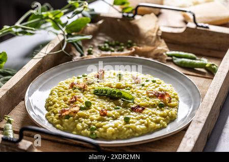 Risotto au safran italien avec petits pois et bacon servis de façon créative dans une assiette. Banque D'Images