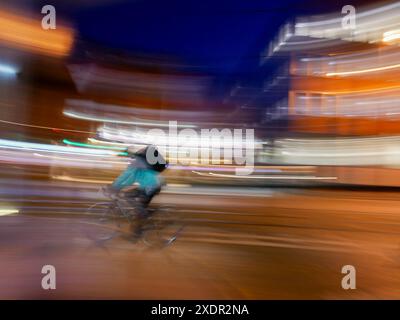 Photo en mouvement longue exposition d'un tramway en mouvement passant devant un livreur Uber Eats dans une rue de la ville la nuit à Sheffield Banque D'Images