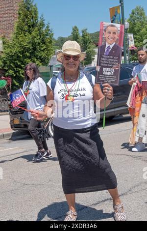 Un membre du Peekskill Seniors Club marche lors de la parade de la quinzième année avec un drapeau et une photo du président Obama. Dans Peekskill, juin 2024. Banque D'Images