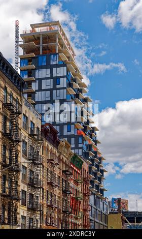 NYC Chinatown : 59 Henry Street, en construction, domine ses voisins ; ses panneaux de verre et de métal entrent en conflit avec des styles centenaires de maçonnerie. Banque D'Images