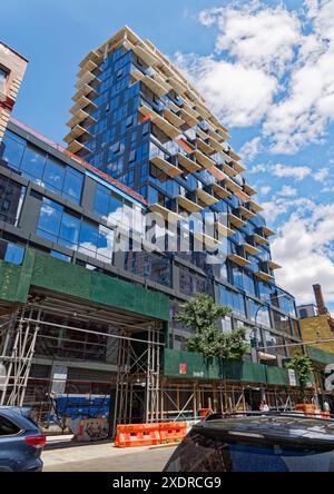 NYC Chinatown : 59 Henry Street, en construction, domine ses voisins ; ses panneaux de verre et de métal entrent en conflit avec des styles centenaires de maçonnerie. Banque D'Images