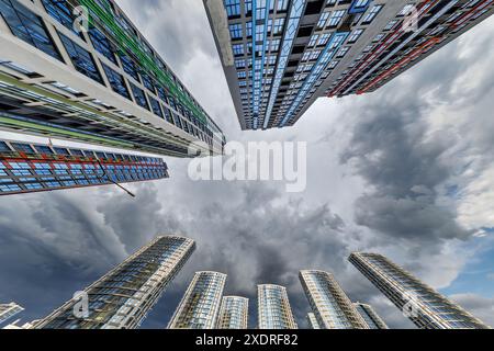 vue d'en bas dans le ciel orageux avec des nuages sombres de grand complexe résidentiel de gratte-ciel moderne Banque D'Images