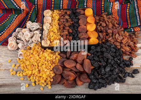 Types de fruits secs. Abricots séchés, raisins secs noirs et légers et figues séchées dans un sac cadeau. Il existe de nombreux types de fruits secs en piles sur le coun Banque D'Images