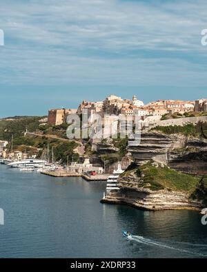 Bonifacio, Corse, France - 27 mai 2024 : un petit canot passe devant la citadelle fortifiée de Bonifacio en Corse lorsqu'il entre dans le port Banque D'Images