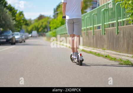 Un homme portant des vêtements de sport décontractés sur scooter électrique. Vue arrière. Le concept d'écologie et de mode de vie sain dans la ville. Banque D'Images