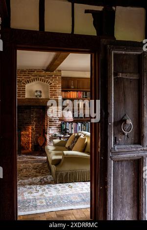 Vue à travers la vieille porte de chêne au salon dans la ferme Tudor du 16ème siècle, Hertfordshire, Angleterre, Royaume-Uni Banque D'Images