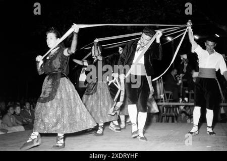 Männer und Frauen in traditioneller Kleidung führen einen Volkstanz auf der Festa major, dem größten Volksfest in San Felíu de Guixols, auf, Katalonien 1957. Hommes et femmes en tenue traditionnelle jouent une danse folklorique à la Festa Major, le plus grand festival folklorique de San Felíu de Guixols, Catalogne 1957. Banque D'Images