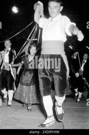 Männer und Frauen in traditioneller Kleidung führen einen Volkstanz auf der Festa major, dem größten Volksfest in San Felíu de Guixols, auf, Katalonien 1957. Hommes et femmes en tenue traditionnelle jouent une danse folklorique à la Festa Major, le plus grand festival folklorique de San Felíu de Guixols, Catalogne 1957. Banque D'Images