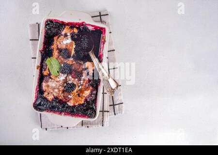 Tarte de cordonnier de mûrier maison sucrée, gâteau de cordonnier de baies d'été doux dans un plat de cuisson en émail et une assiette, sur un espace de copie de table de cuisine blanc Banque D'Images