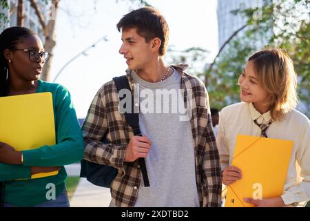 Trois amis étudiants multiethniques marchant en classe à l'université, parlant joyeusement. Banque D'Images
