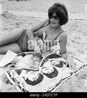 Beach fashion 1964, dernière en lotion de bronzage, tube - femme lisant magazine sur une serviette Beatles. Photo de Harry pot, Anefo Banque D'Images