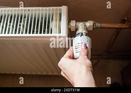 Réglage manuel de la température sur le thermostat du radiateur de chauffage, concept économique. Tourner le bouton du radiateur de chauffage pour contrôler la chaleur dans la maison. Augmentant ou diminuant Banque D'Images