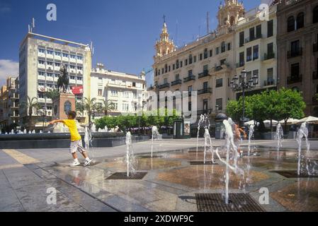 Les enfants se rafraîchissent dans une fontaine lors d'une chaude journée d'été sur la Plaza Espana de Saragosse, en Espagne Banque D'Images