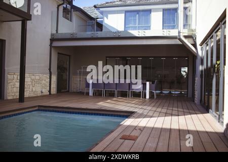 Maison moderne avec terrasse en bois et piscine dans un patio arrière spacieux, espace copie Banque D'Images