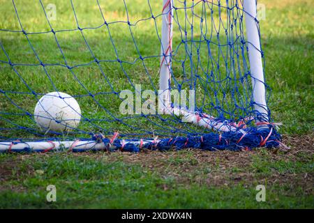 Ballon de football au but. But de football dans le terrain de football avec la lumière du soleil le matin Banque D'Images