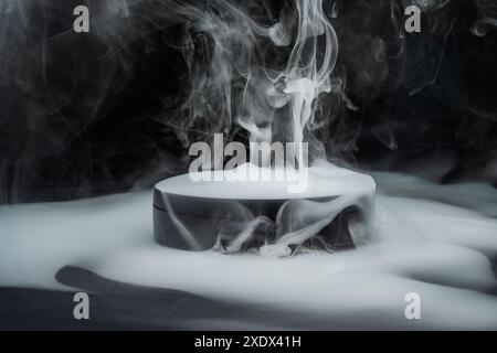 Podium noir élégant entouré de fumée blanche bouillonnante sur un fond sombre, créant une ambiance élégante et mystérieuse, parfaite pour présenter des produits Banque D'Images