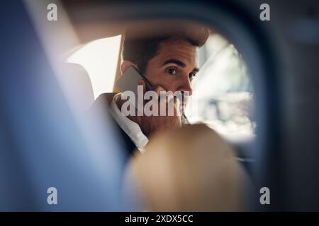 Miroir de voiture, appel téléphonique et homme d'affaires en taxi pour voyage, voyage ou trajet avec productivité. Transport, véhicule ou entrepreneur dans le siège arrière de la cabine Banque D'Images