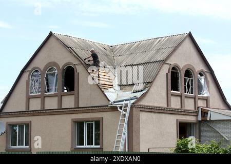 Non exclusif : Vasylkiv, UKRAINE - 23 JUIN 2024 - Un homme répare le toit d'une maison endommagée par une attaque de missile russe, Vasylkiv, région de Kiev, Nord Banque D'Images