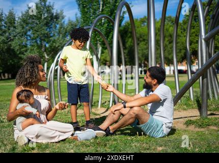 Famille vénézuélienne avec deux enfants, un garçon de 8 ans et un bébé de 6 mois ensemble dans un parc par une journée ensoleillée Banque D'Images