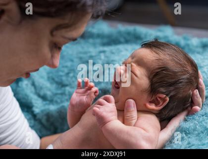 Une mère aimante prend soin de son nouveau-né. portrait d'une mère tenant un bébé qui pleure dans ses bras. Mère embrasse son petit fils. Banque D'Images