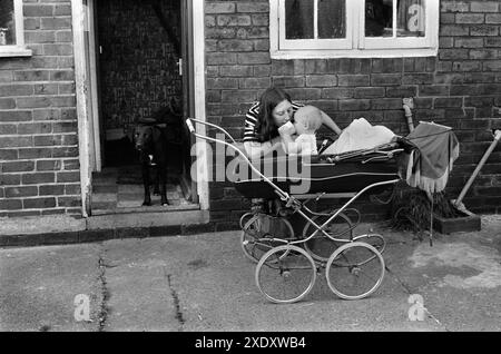 Pit Mining Village vie de famille des années 1970 Grande-Bretagne. Mme Carol Backhouse et bébé Craig en poussette. Snoopy dans la porte de leur maison sur le domaine Northfield. C'est l'arrière de leur maison. South Kirkby Colliery, Yorkshire, Angleterre 1979 HOMER SYKES Banque D'Images