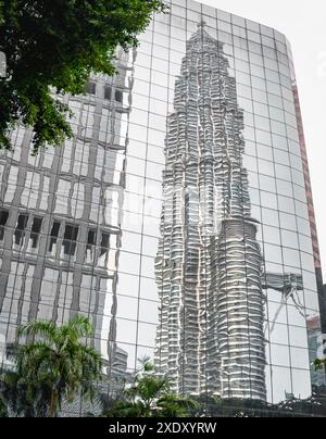 L'une des tours emblématiques est reflétée par la surface brillante d'une structure vitrée miroir moderne voisine, donnant une vue abstraite de la célèbre tour. Banque D'Images