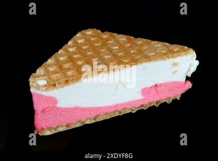 Gâteau fait de gaufres triangulaires et crème glacée rose crémeuse isolé sur noir Banque D'Images