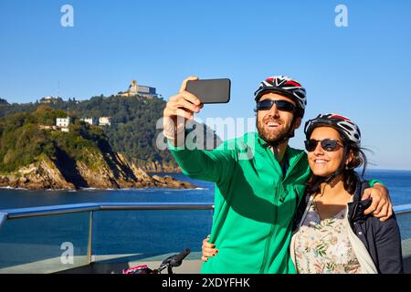 Couple de touristes, faisant une selfies en vélo à travers la ville, La Baie de la Concha, Donostia, San Sebastian, Gipuzkoa, Pays Basque, Espagne, Europe Banque D'Images