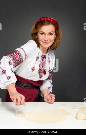 Femme adulte dans le style ukrainien traditionnel. Cuisine ukrainienne varenyky avec des cerises. Série. Banque D'Images