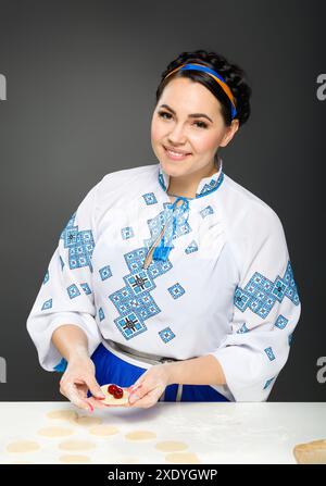 Femme adulte dans le style ukrainien traditionnel. Cuisine ukrainienne varenyky avec des cerises. Série. Banque D'Images