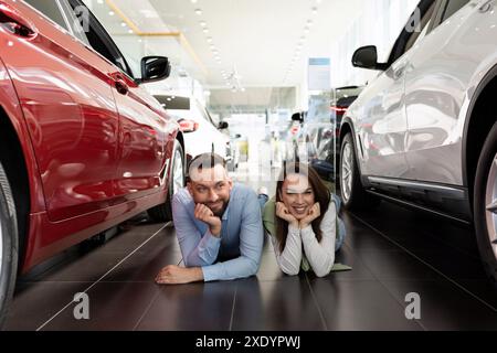 Un couple marié charismatique gai se trouve dans un concessionnaire automobile entre voitures et rêves d'acheter une nouvelle voiture Banque D'Images