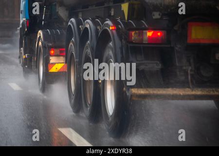 Le débit d'eau de pluie provenant des roues d'un camion lourd se déplace rapidement en ville de jour avec une attention sélective. Banque D'Images