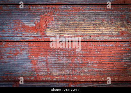 Anciennes planches en bois naturellement altérées avec fond de peinture rouge craquelé Banque D'Images