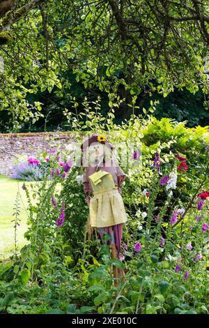 Un épouvantail dans un parterre de fleurs de jardin. Banque D'Images
