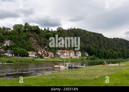 Une rivière avec quelques bateaux flottant dessus. La rivière est entourée d'une colline verdoyante. Le ciel est nuageux et l'atmosphère est calme et paisible Banque D'Images